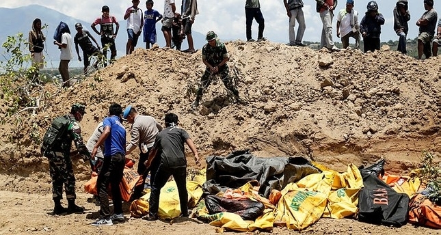 Mass grave dug to bury victims of quake, tsunami in Indonesia